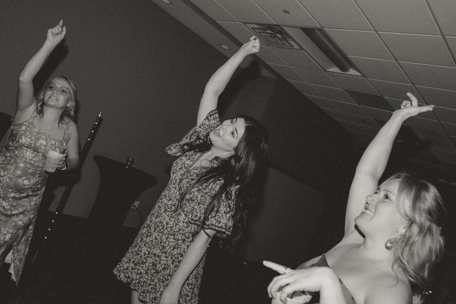 Guests dancing with arms raised at a dark indoor celebration.