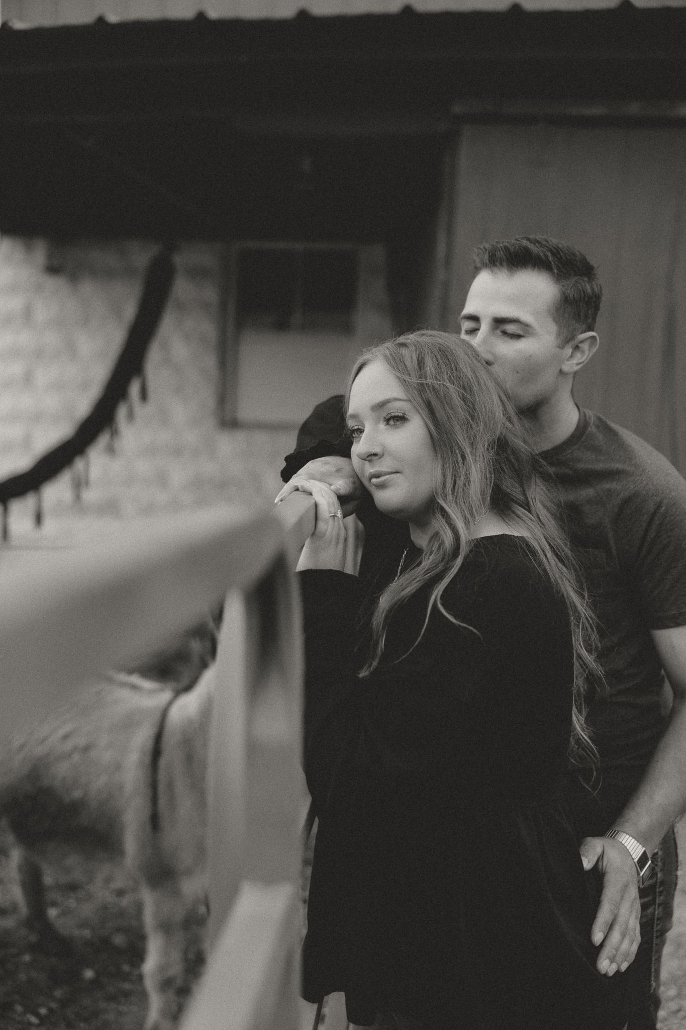 A black and white portrait of a couple sharing an intimate moment outdoors.