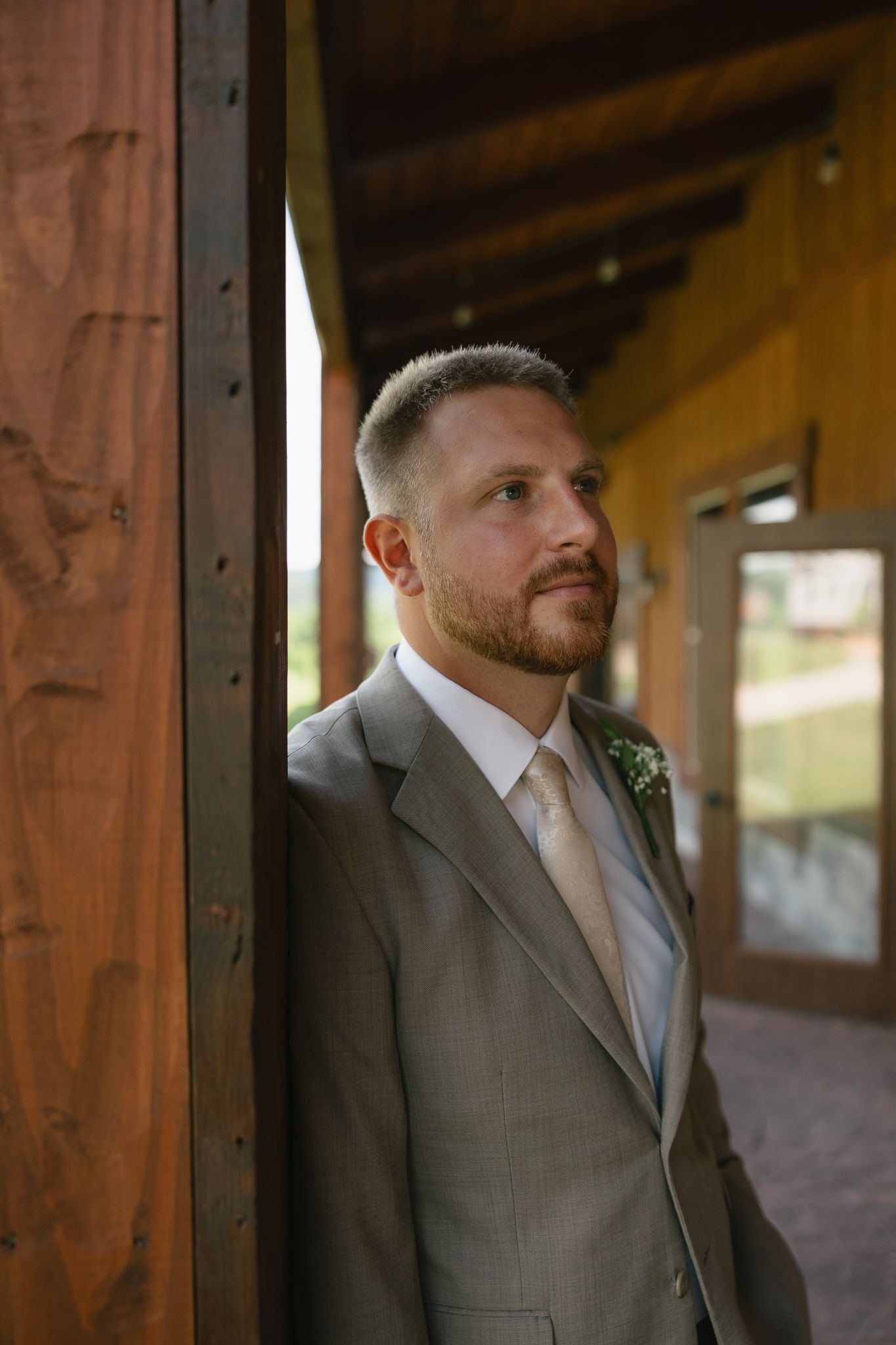 Portrait sequence of someone in a grey suit standing against wooden beams in natural light.