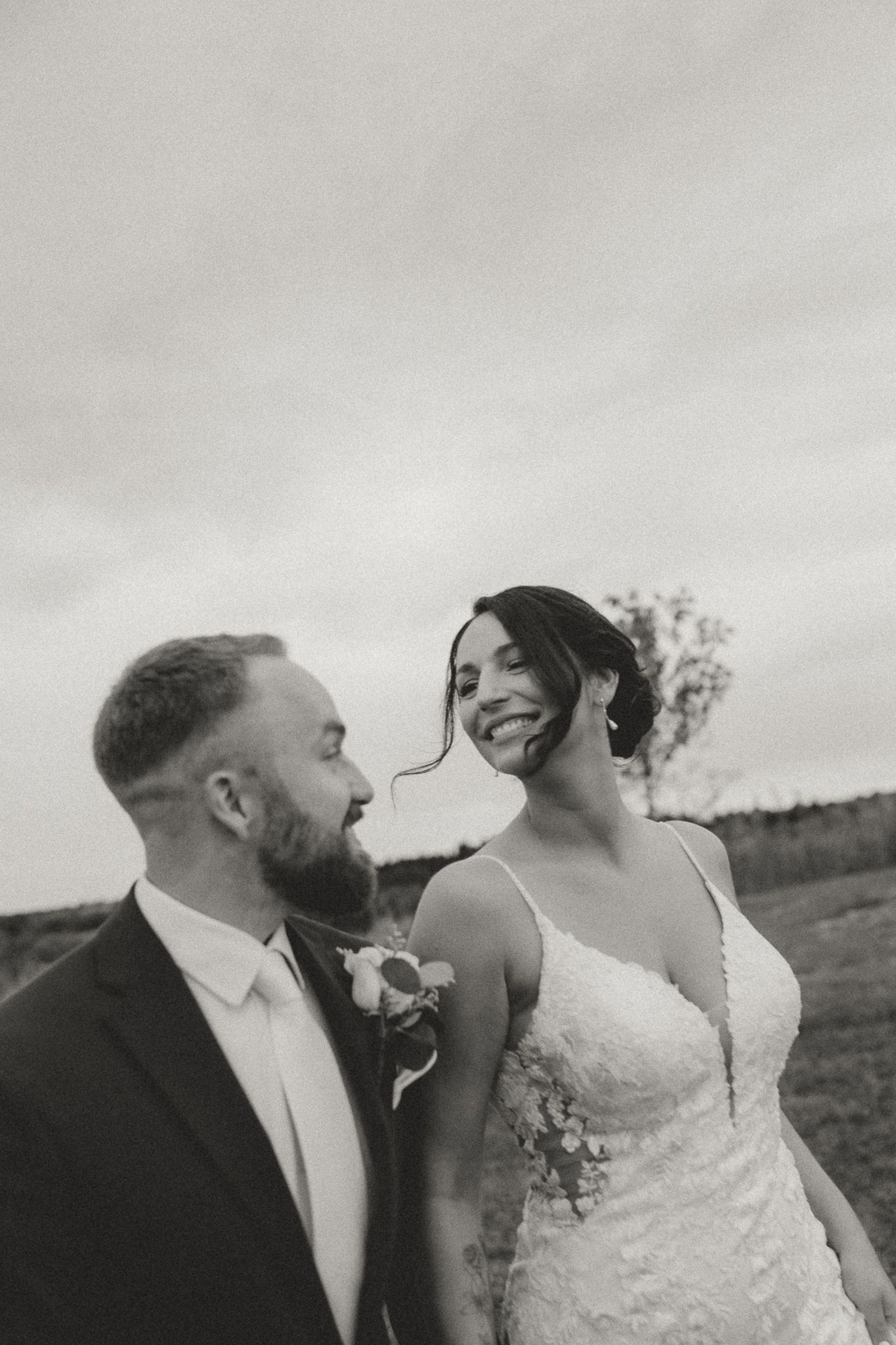 Black and white candid wedding portrait capturing a joyful moment between newlyweds.