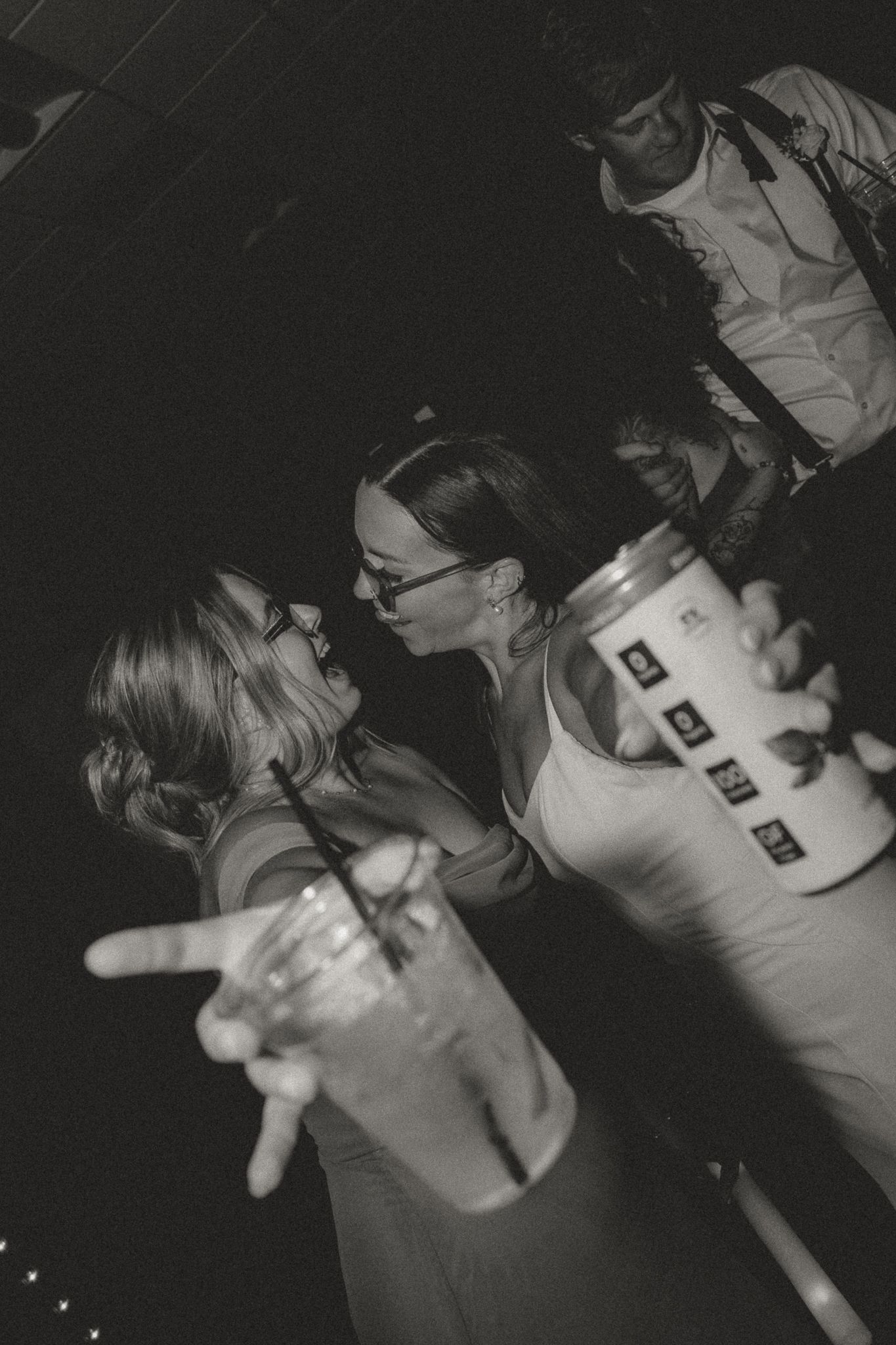 A black and white photo captures party guests laughing and holding drinks at an event.