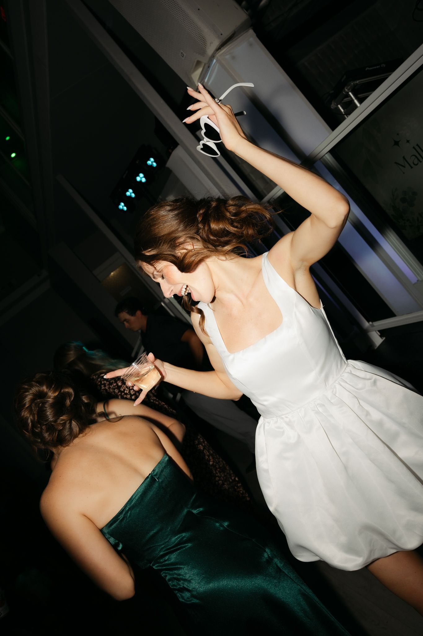 Two guests dancing energetically, one in white dress and one in emerald green.