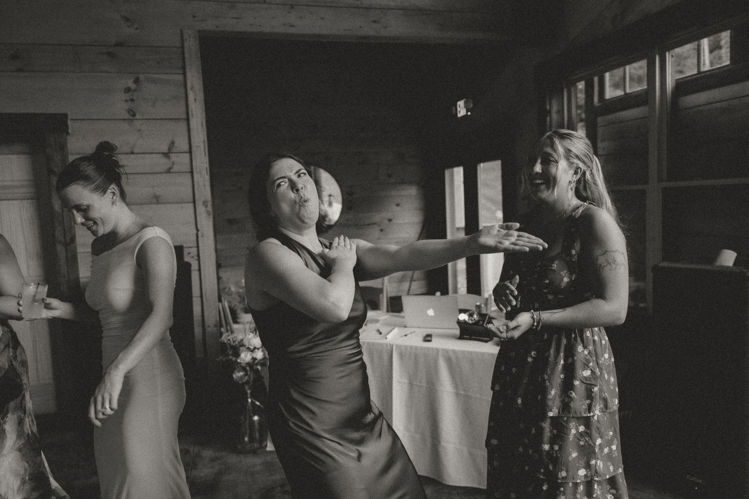 Wedding guests mingling in a rustic indoor venue with wooden walls.