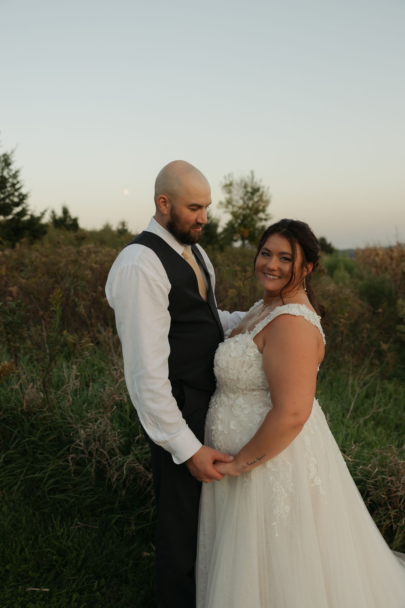 Sunset wedding portrait captures tender moment between couple in natural setting.