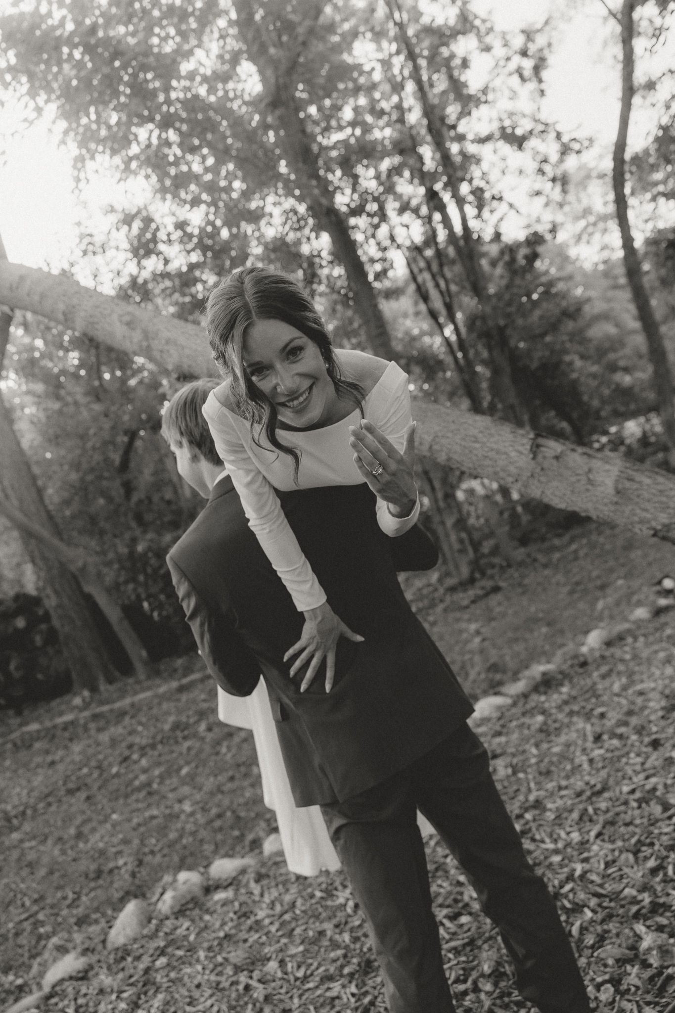 A candid black and white photo shows a playful moment between newlyweds.