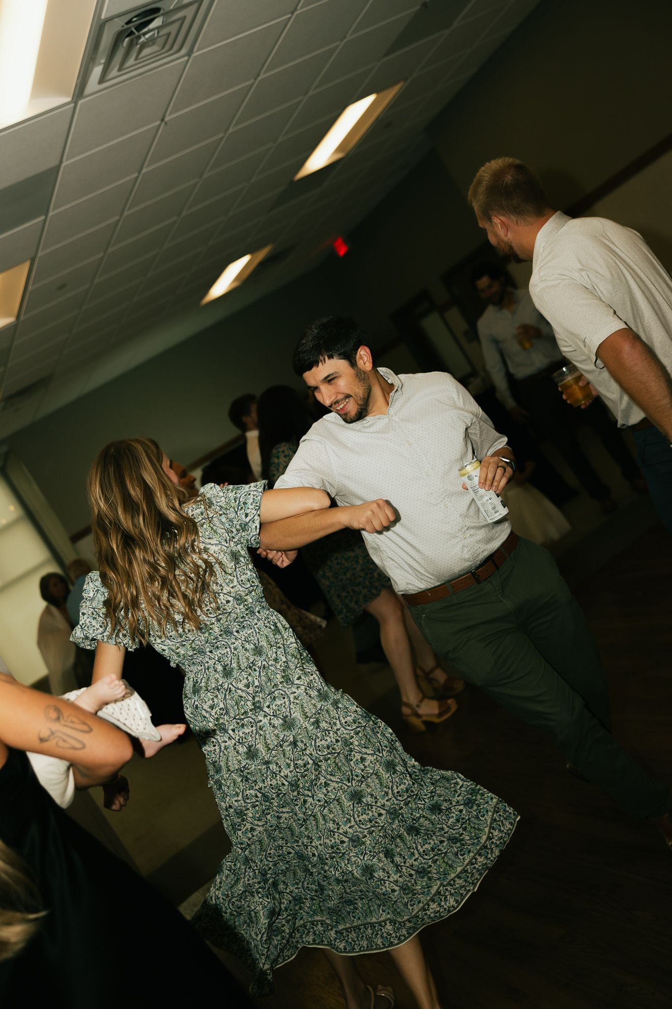 Couples dancing at a wedding reception under fluorescent lights.