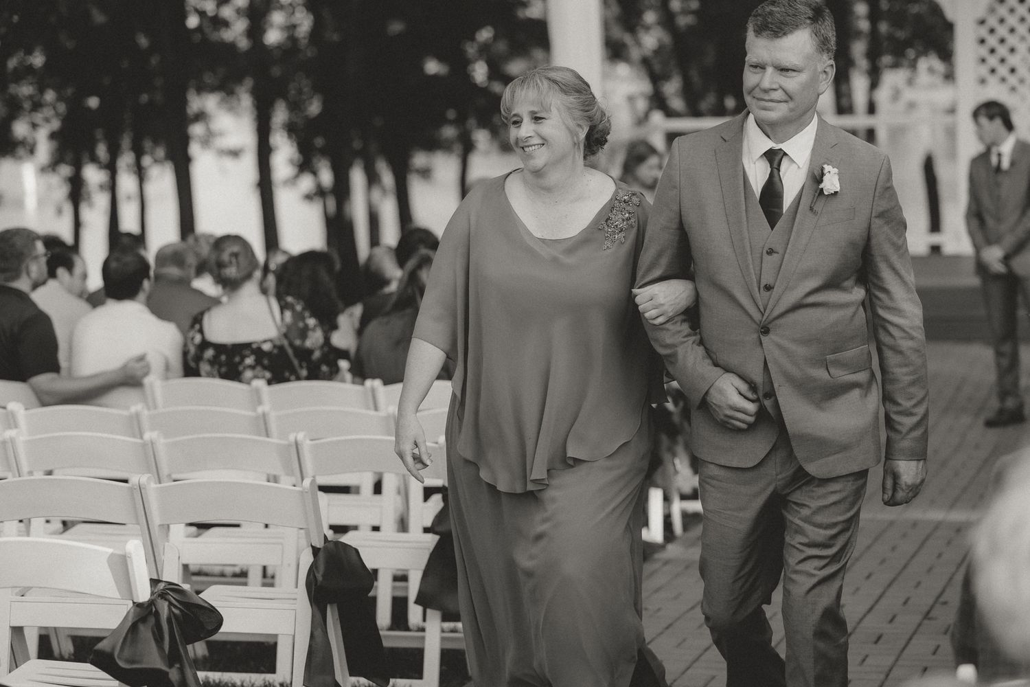 Wedding guests in formal attire gather outdoors during the celebration.