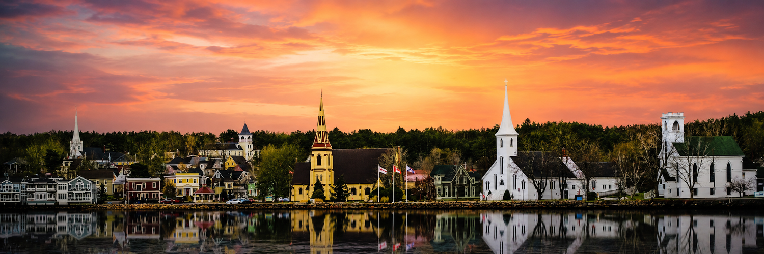 In Mahone Bay Nova Scotia Stunning panoramic sunset over a small New reflected in calm water, with churches and colorful autumn foliage.