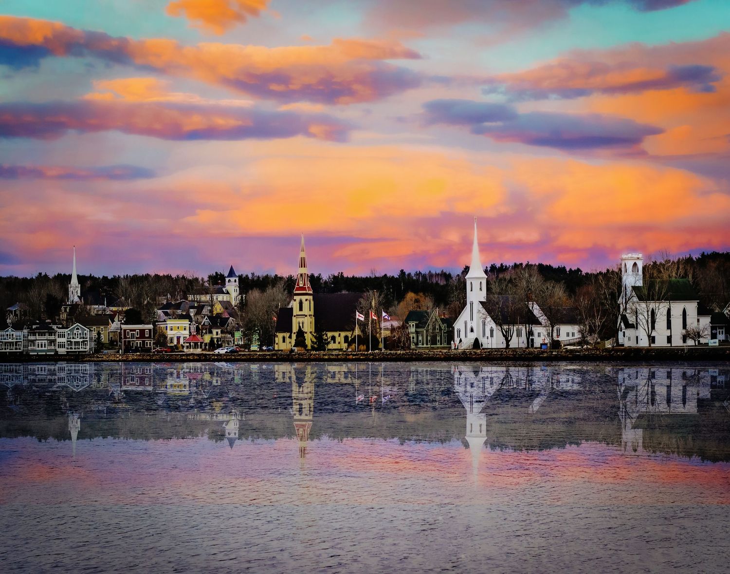 Colorful sunset sky reflecting over a small waterfront town with white churches and trees mirrored in calm water.