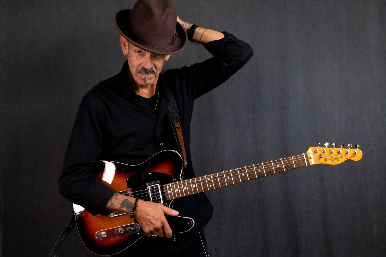 Hubbards Musician in studio for branding session Male guitarist in black shirt and brown hat holding electric sunburst