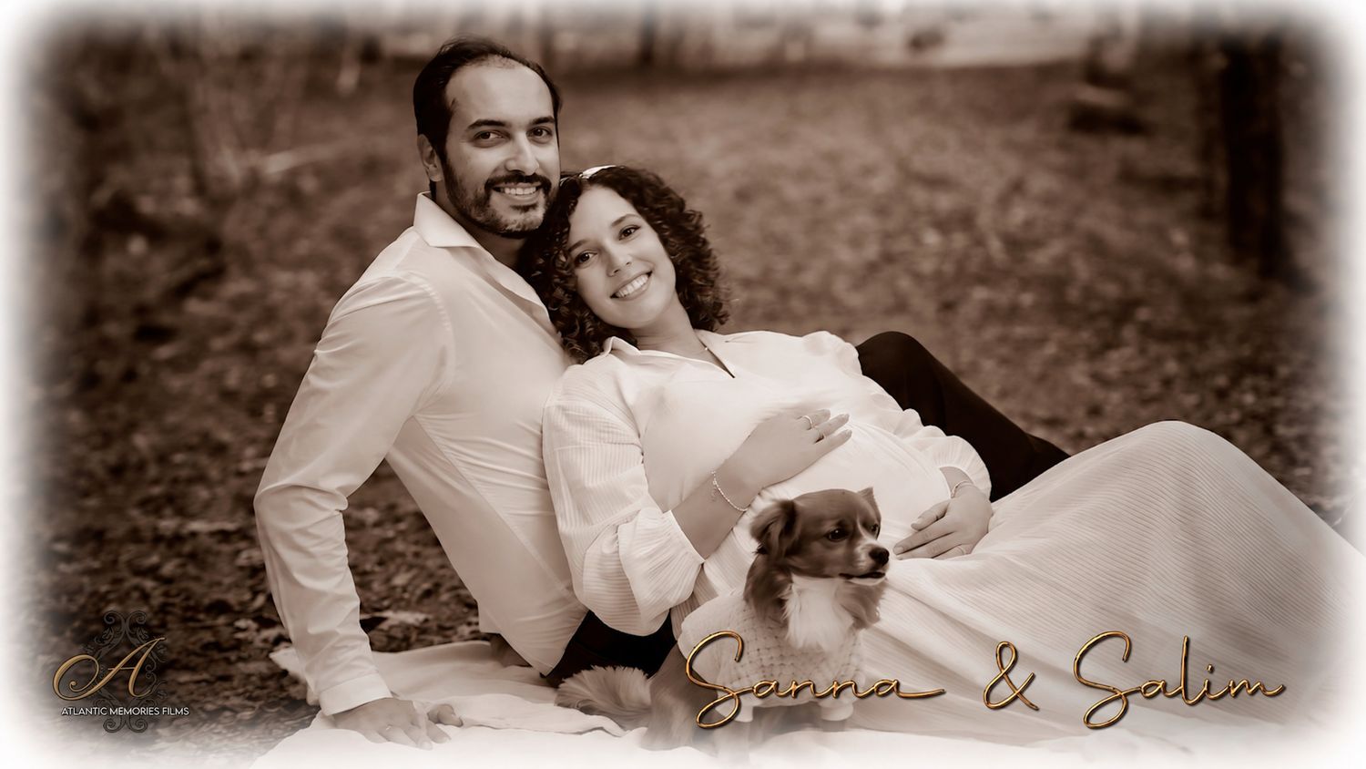 Sepia-toned romantic portrait of couple Seanna and Salim sitting outdoors with a small puppy, wearing white outfits.