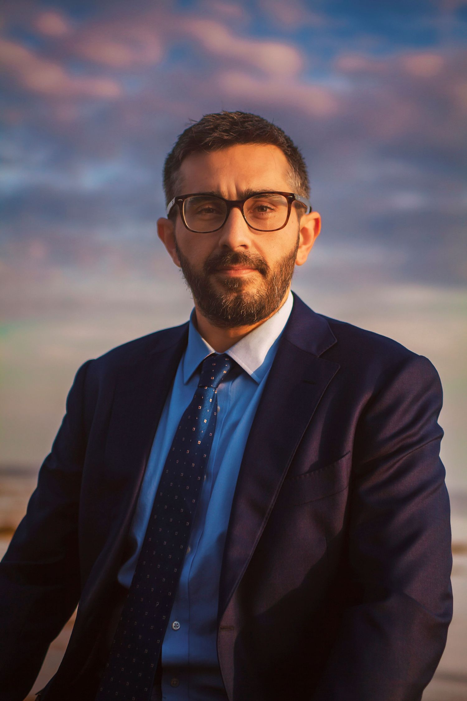 Professional headshot session in Chester ns man with beard and glasses wearing a navy suit and tie poses outdoors at Graves Island