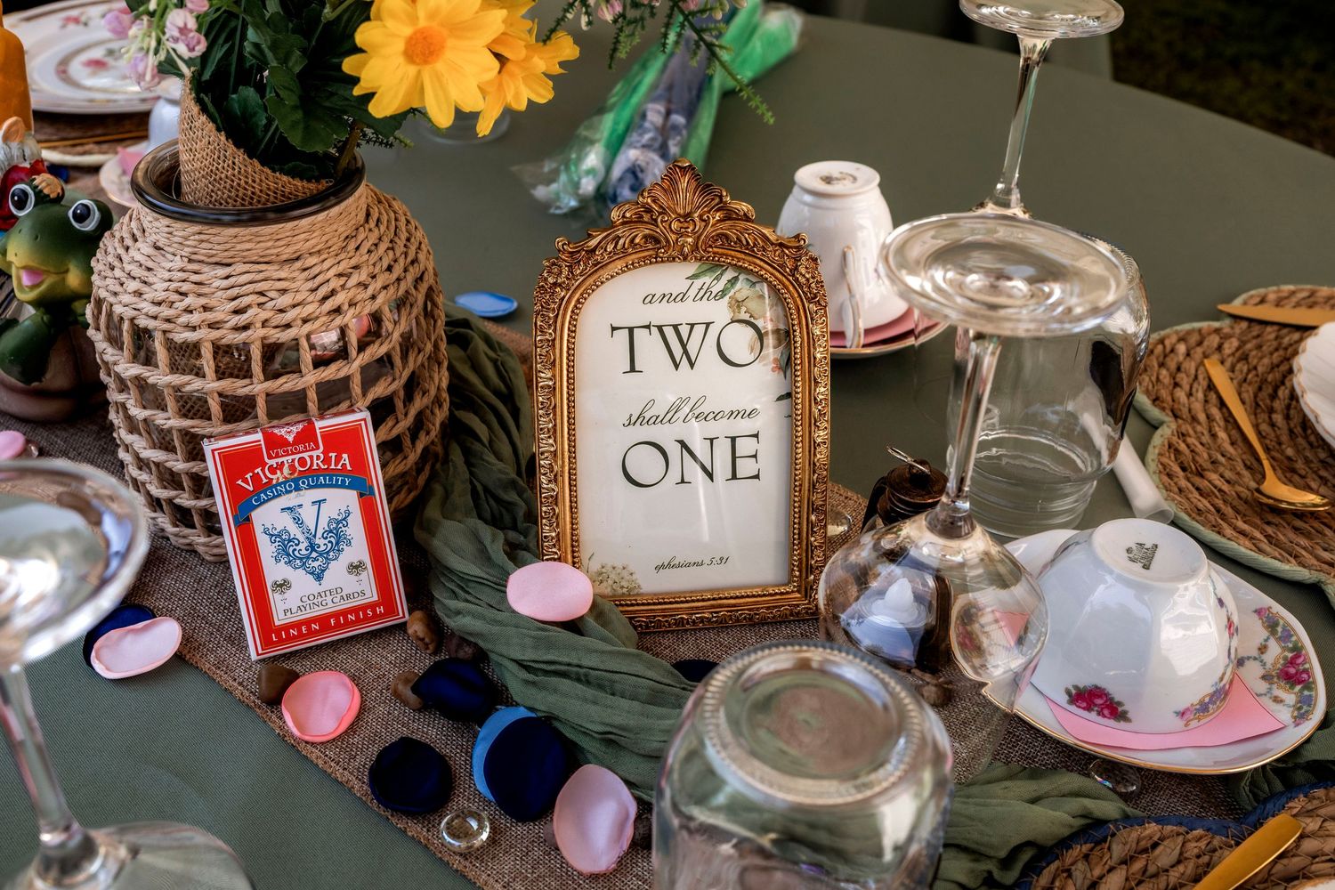 Wedding table decor with table number two sign, teacups, wine glasses, and colorful floral centerpiece.