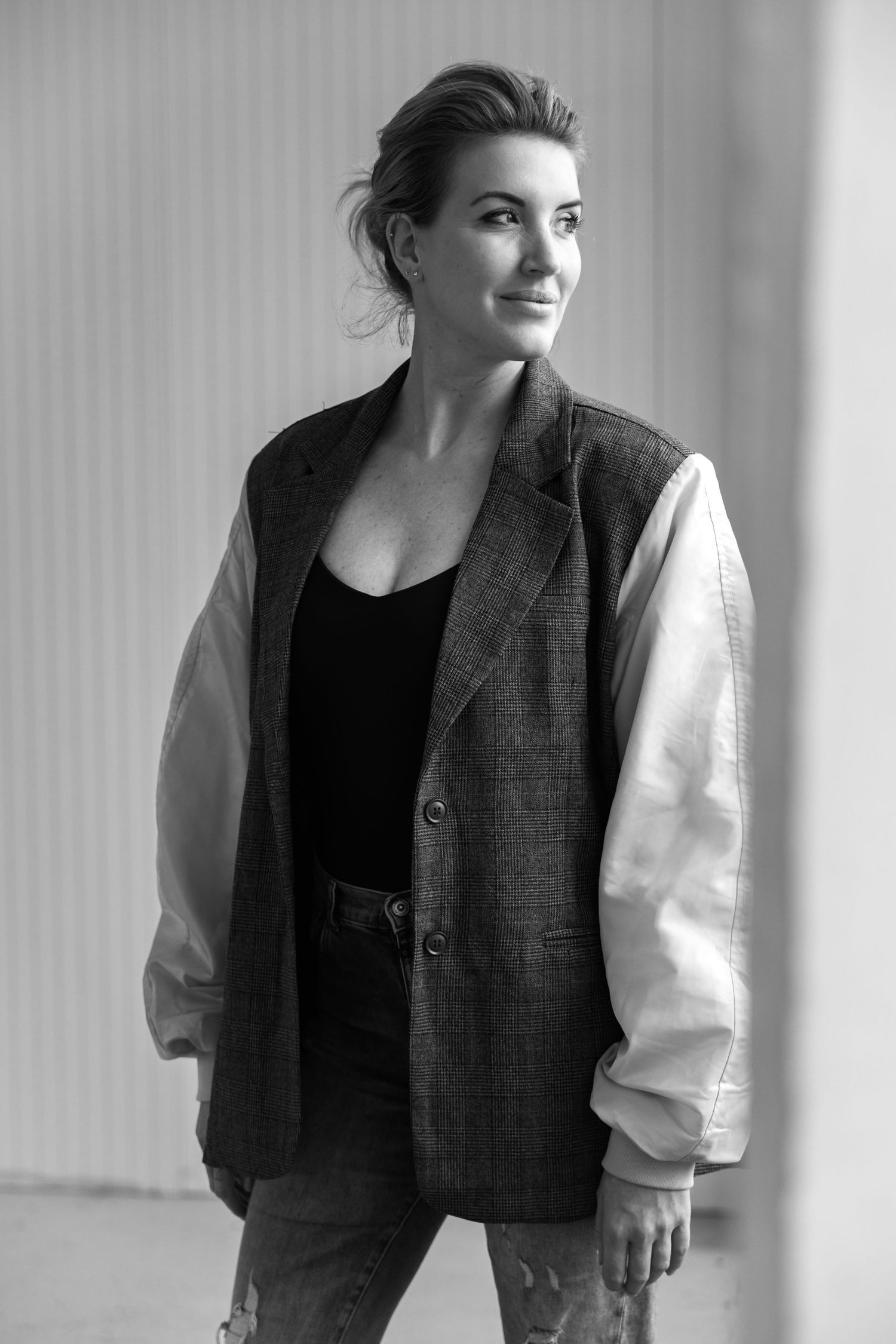 Black and white portrait of a stylish woman in an oversized blazer and jeans, looking confidently to the side.