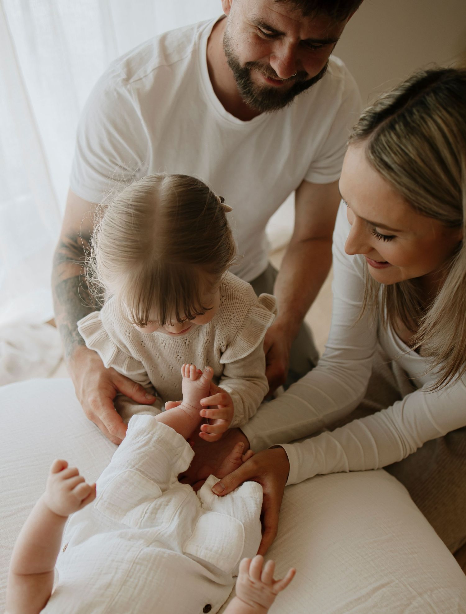 Family sharing intimate moment together on white bedding.