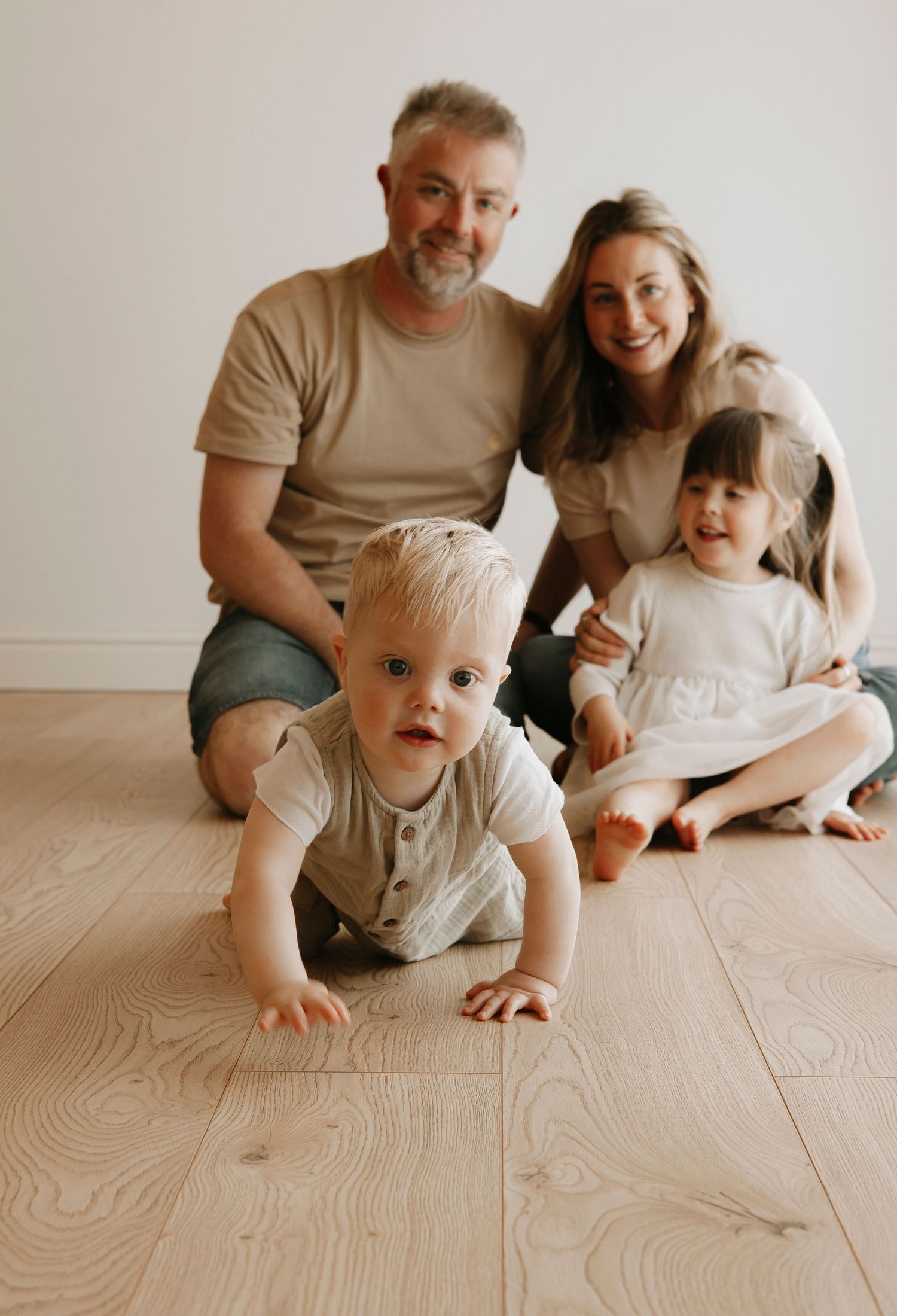 Family playing together on light wooden floor.