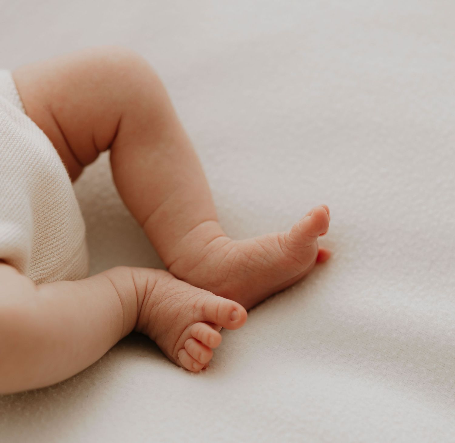Baby's tiny feet resting on soft white fabric.