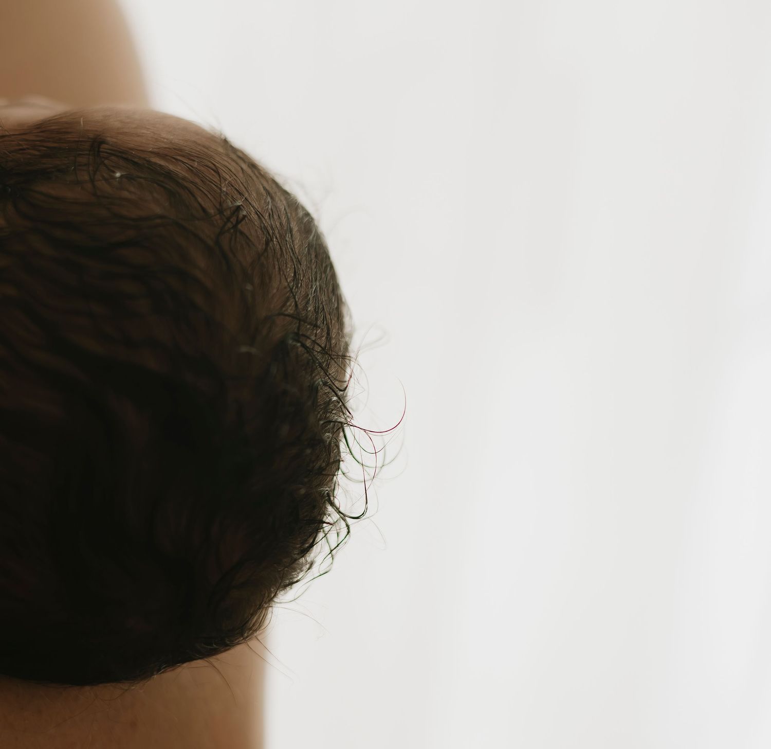 Close-up series of a baby's head and dark hair against a light background.