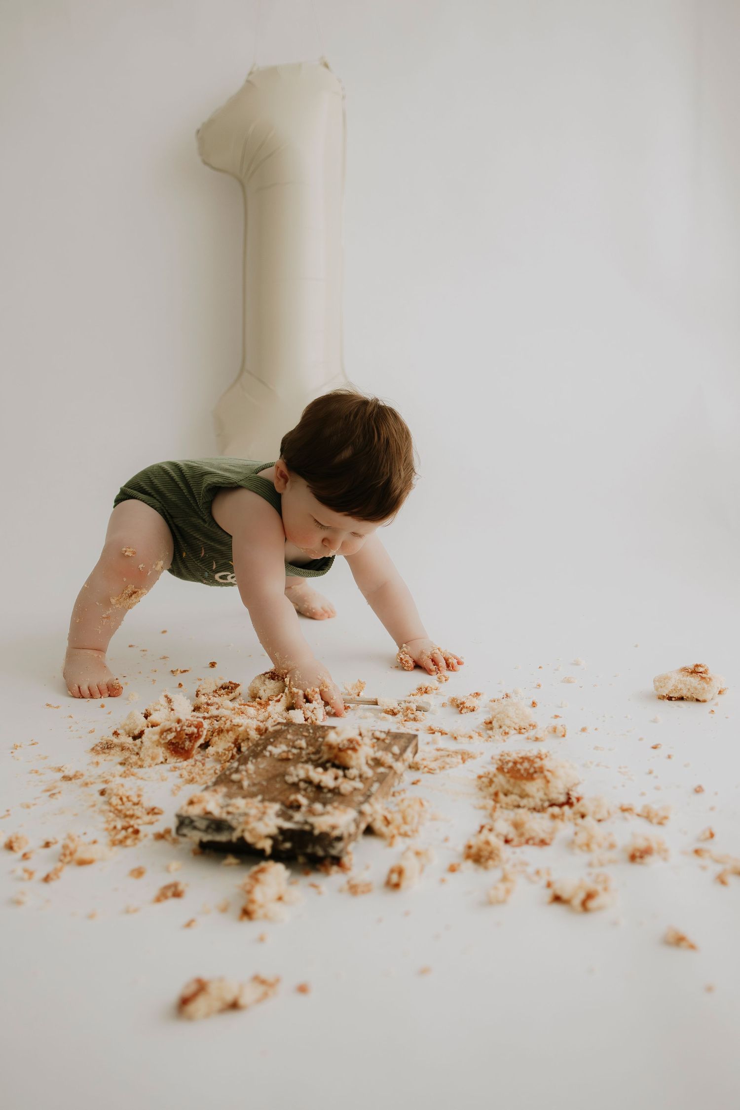 Messy cake crumbs scattered on white floor as small figure explores.