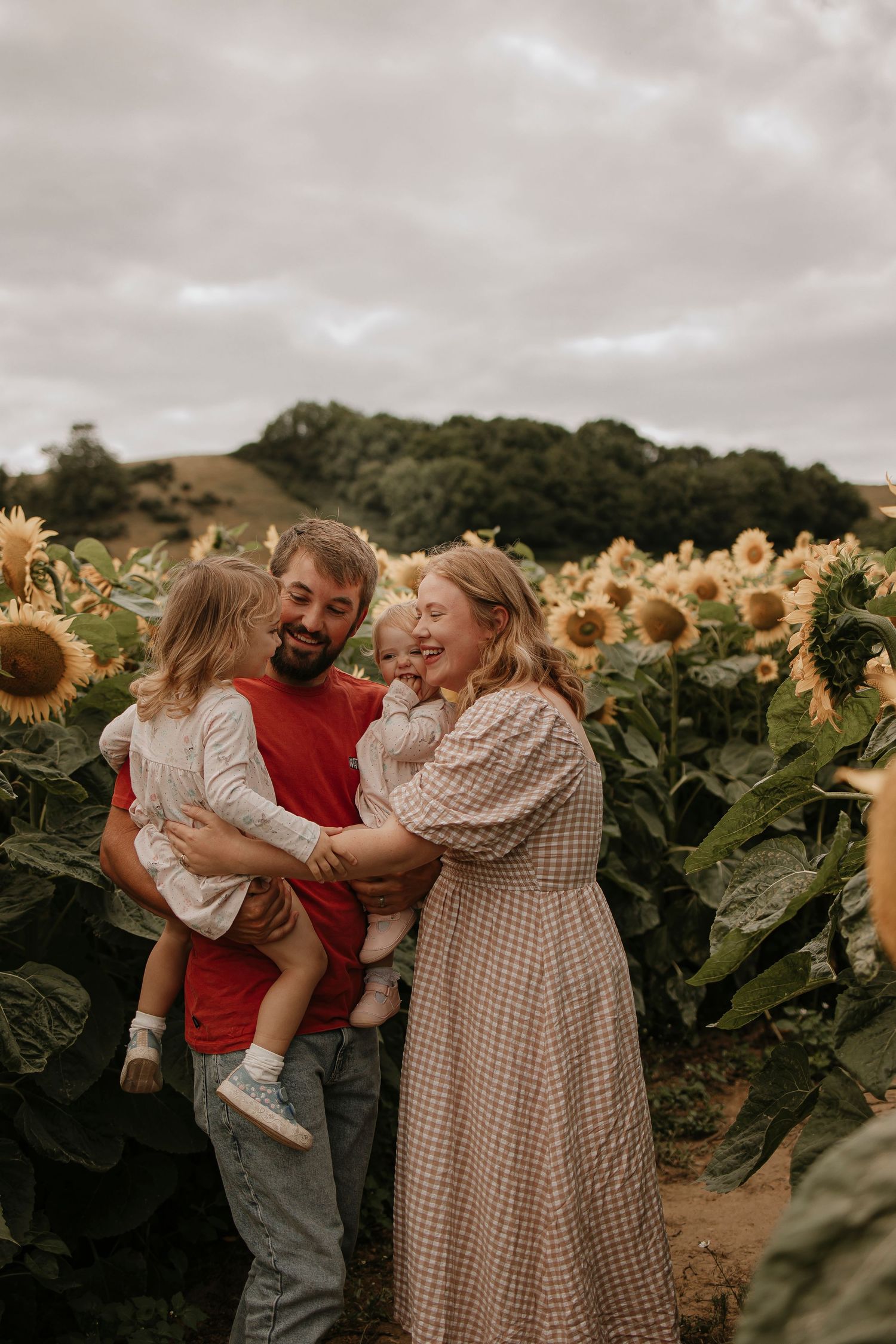 Family sharing joyful moment in sunflower field at sunset.