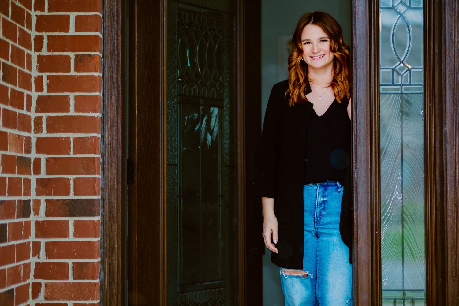 Woman in casual attire standing in doorway of brick building.
