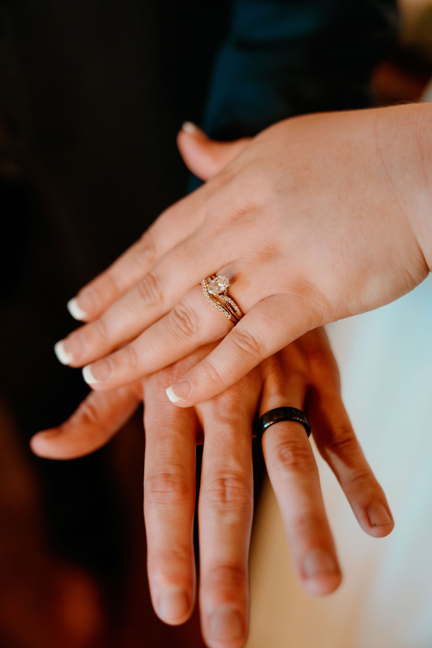 Close-up of wedding rings on couple's hands showing both gold and black bands.