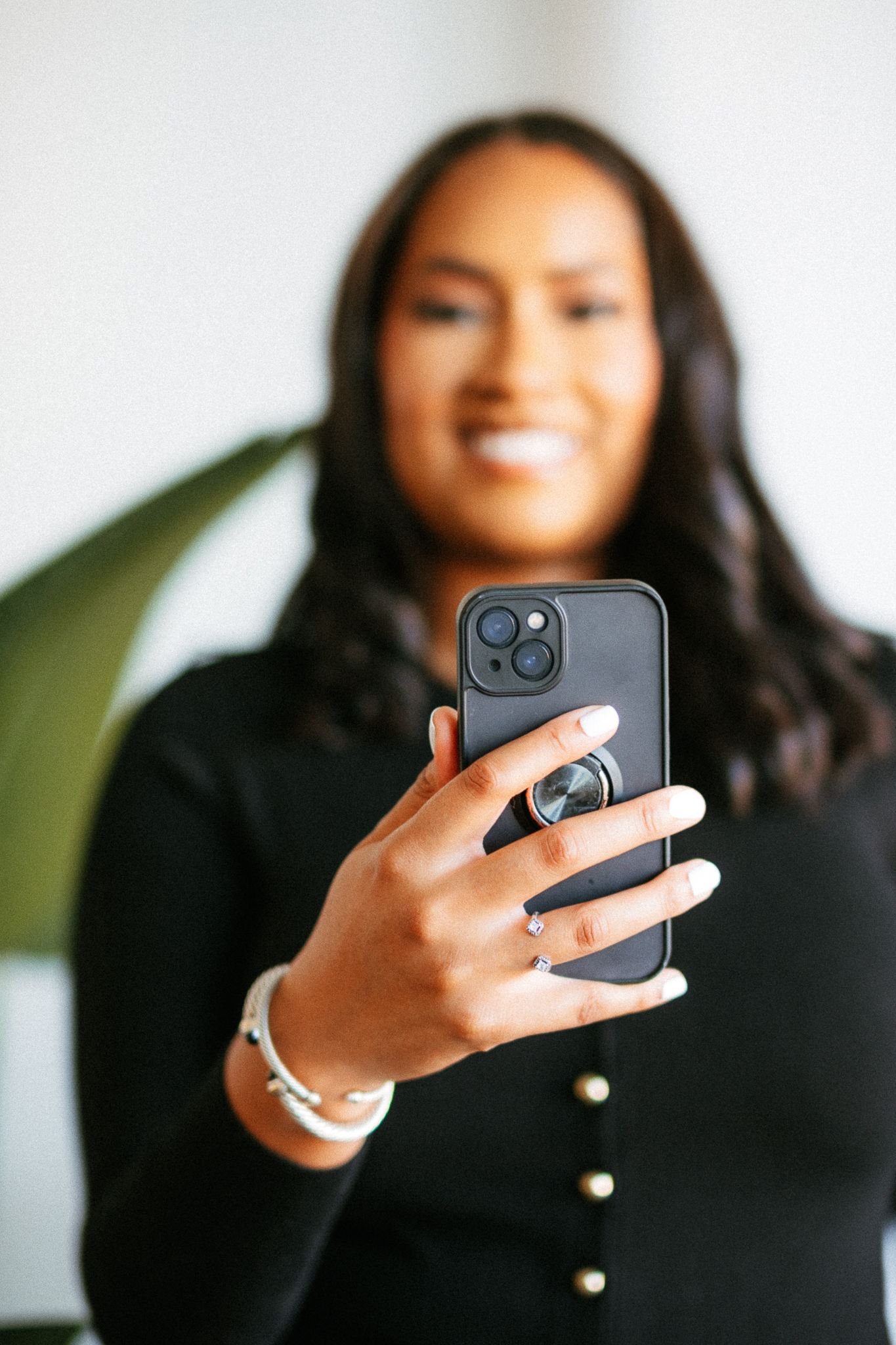 Person holding iPhone with ring light and pop socket in casual indoor setting.