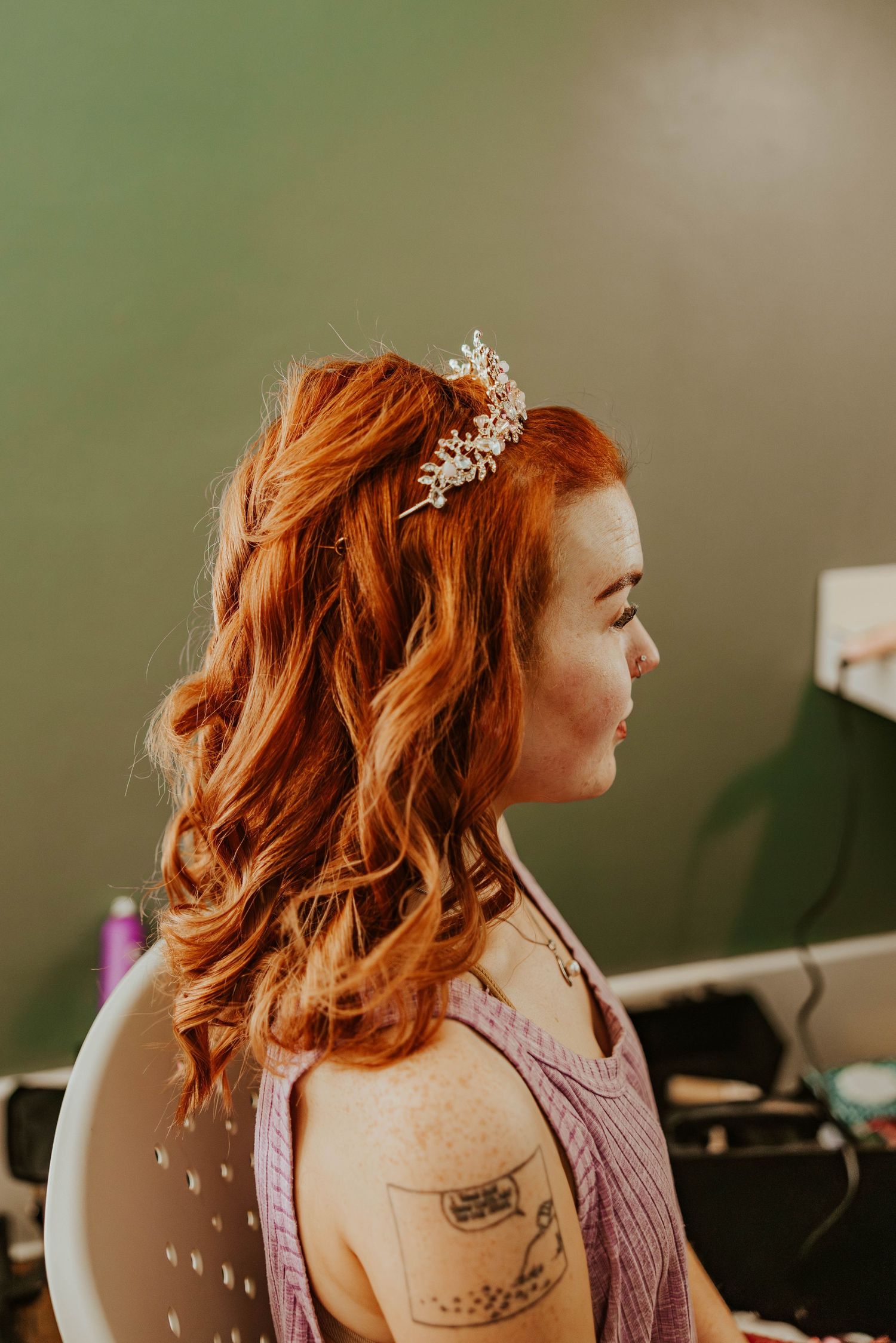 Side profile of wavy red hair adorned with a delicate crystal hairpiece.