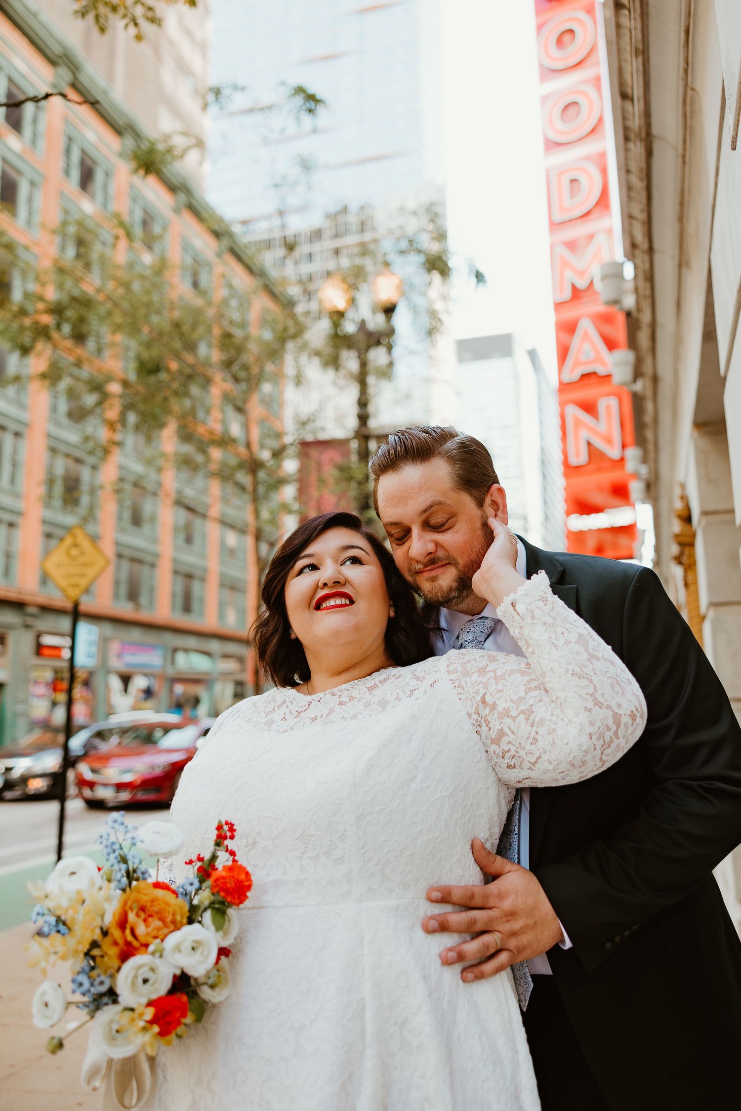 Wedding couple posing on urban street with vintage theater sign in background.
