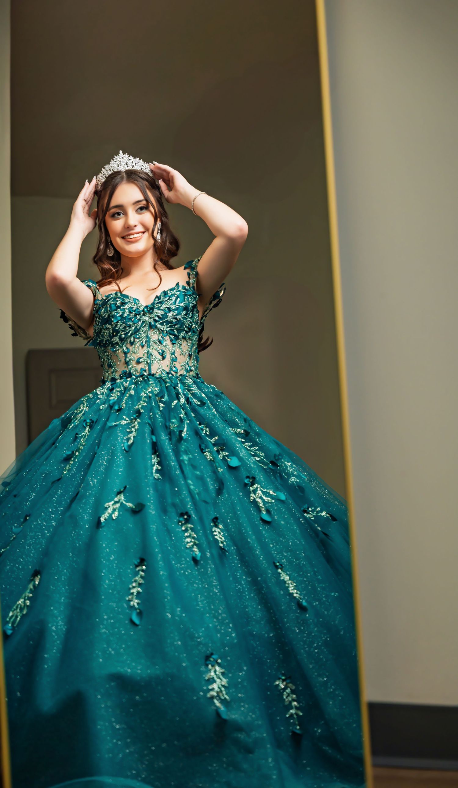 A person wearing a glamorous teal ballgown with floral embroidery twirls in a sequence of elegant poses.