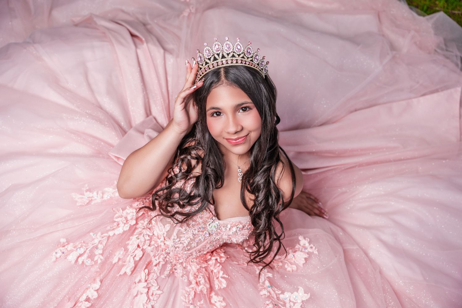 Woman in pink tulle gown sitting on sofa in dreamy feminine boudoir photoshoot setting.