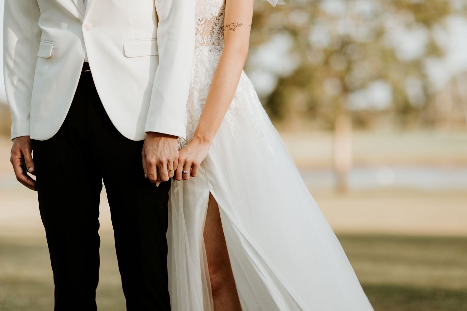 Elegant white wedding dress detail shot against natural outdoor backdrop.
