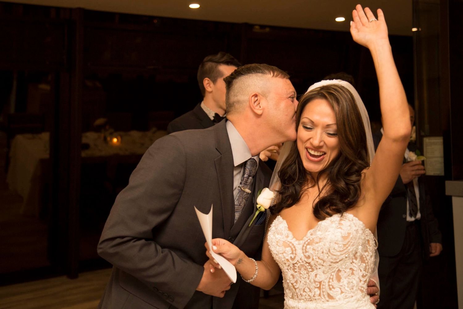 A couple shares an intimate dance moment at their wedding reception in a dimly lit venue.