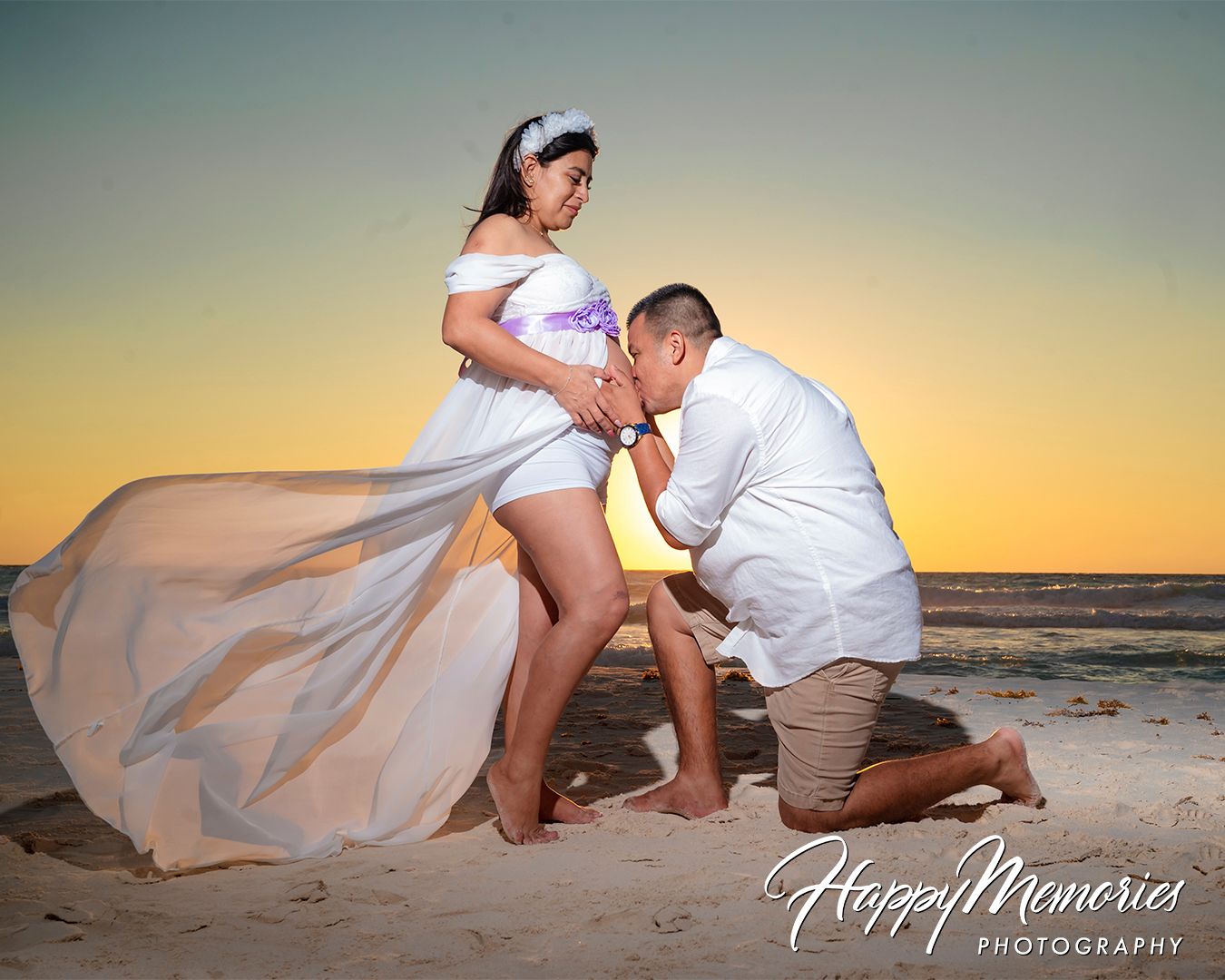 Intimate beach photography session at golden hour with couple in white attire on sandy shore.