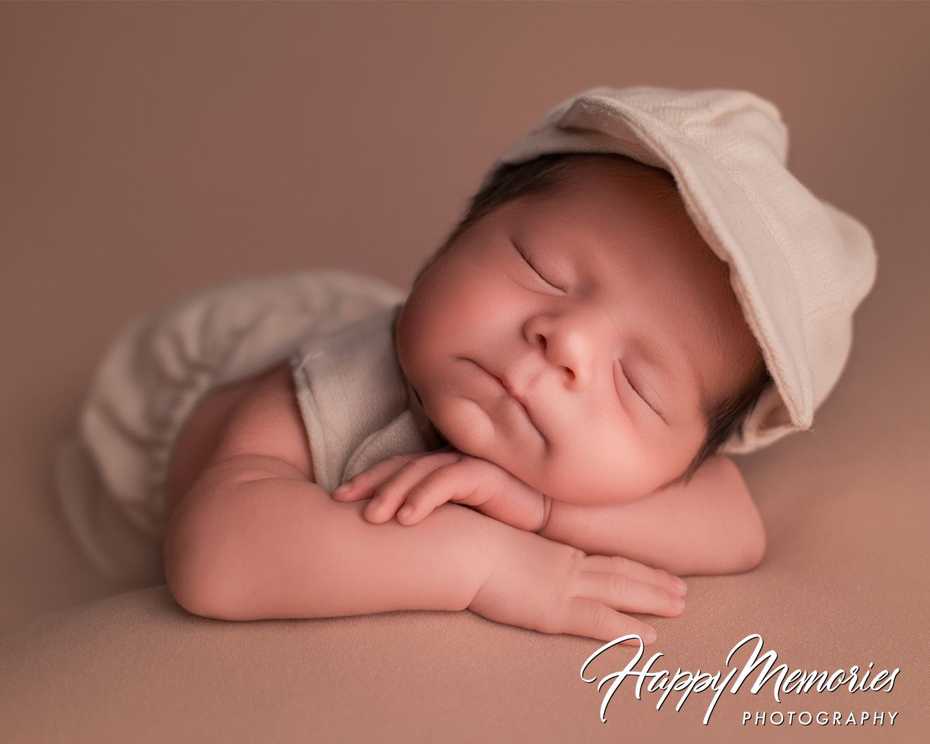 Peaceful newborn portraits with baby wearing vintage-style bonnet against warm brown backdrop.