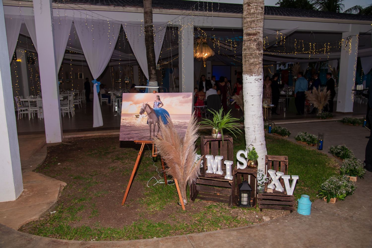 Outdoor event space decorated with white draping fabric and string lights.
