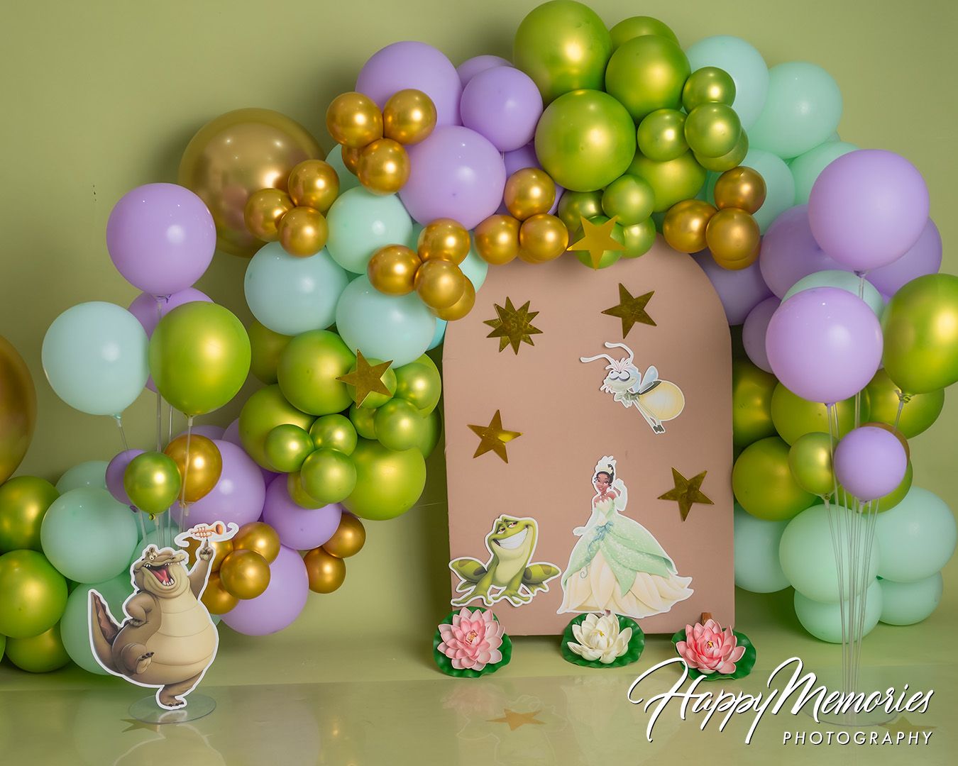 Pastel balloon arch with gold accents frames a princess-themed backdrop featuring whimsical stars and carriage decorations.