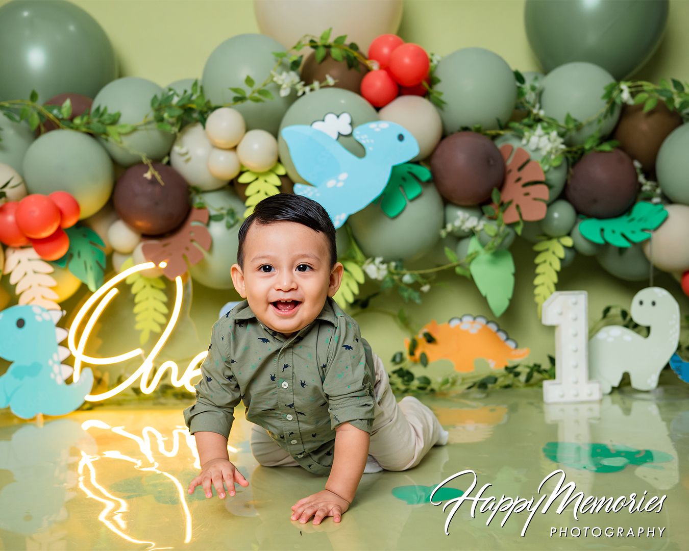 Jungle themed cake smash photo session with green balloons and safari animal decorations.