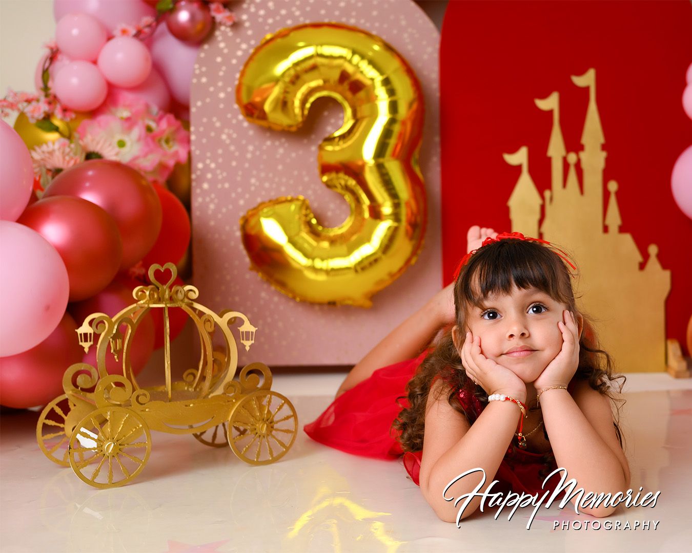 Pink and gold balloon decorations with a carriage silhouette create an elegant princess-themed party setting.