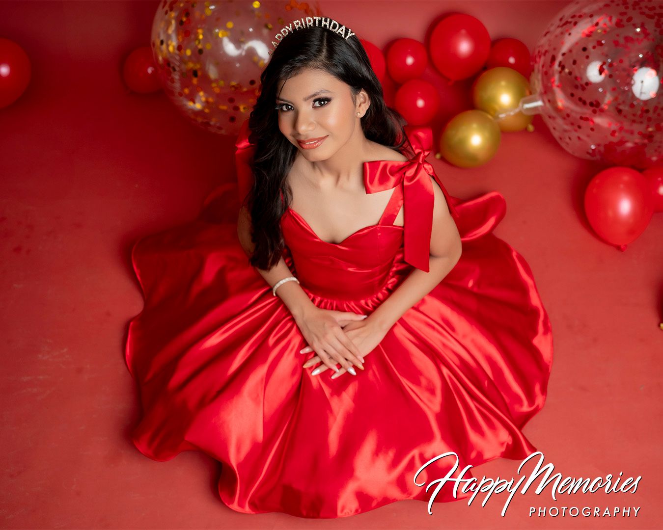 Elegant portrait session in flowing red gown with festive balloon decorations.