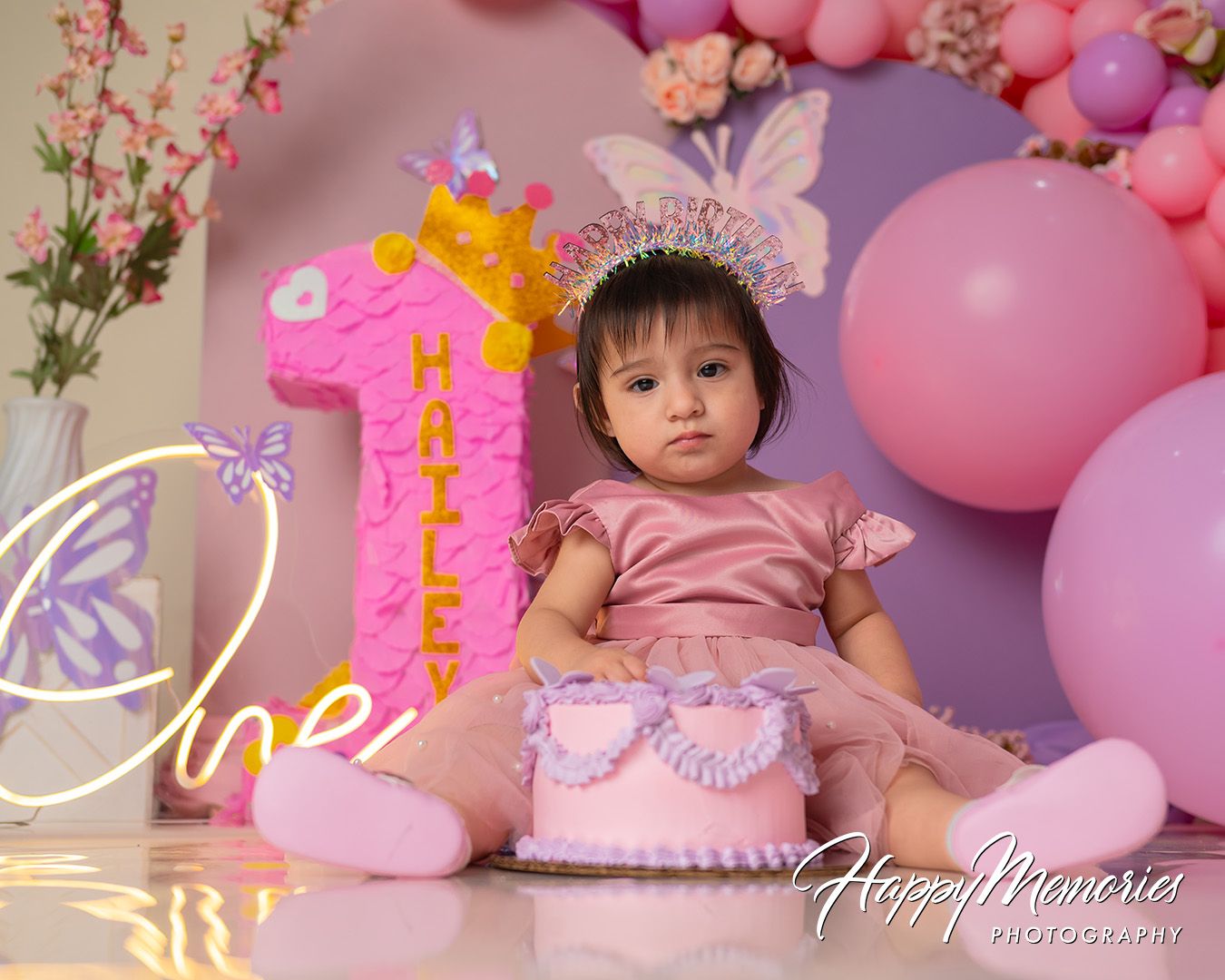 Pink and purple first birthday party decorations with balloons, butterflies, and floral accents create a magical celebration setup.