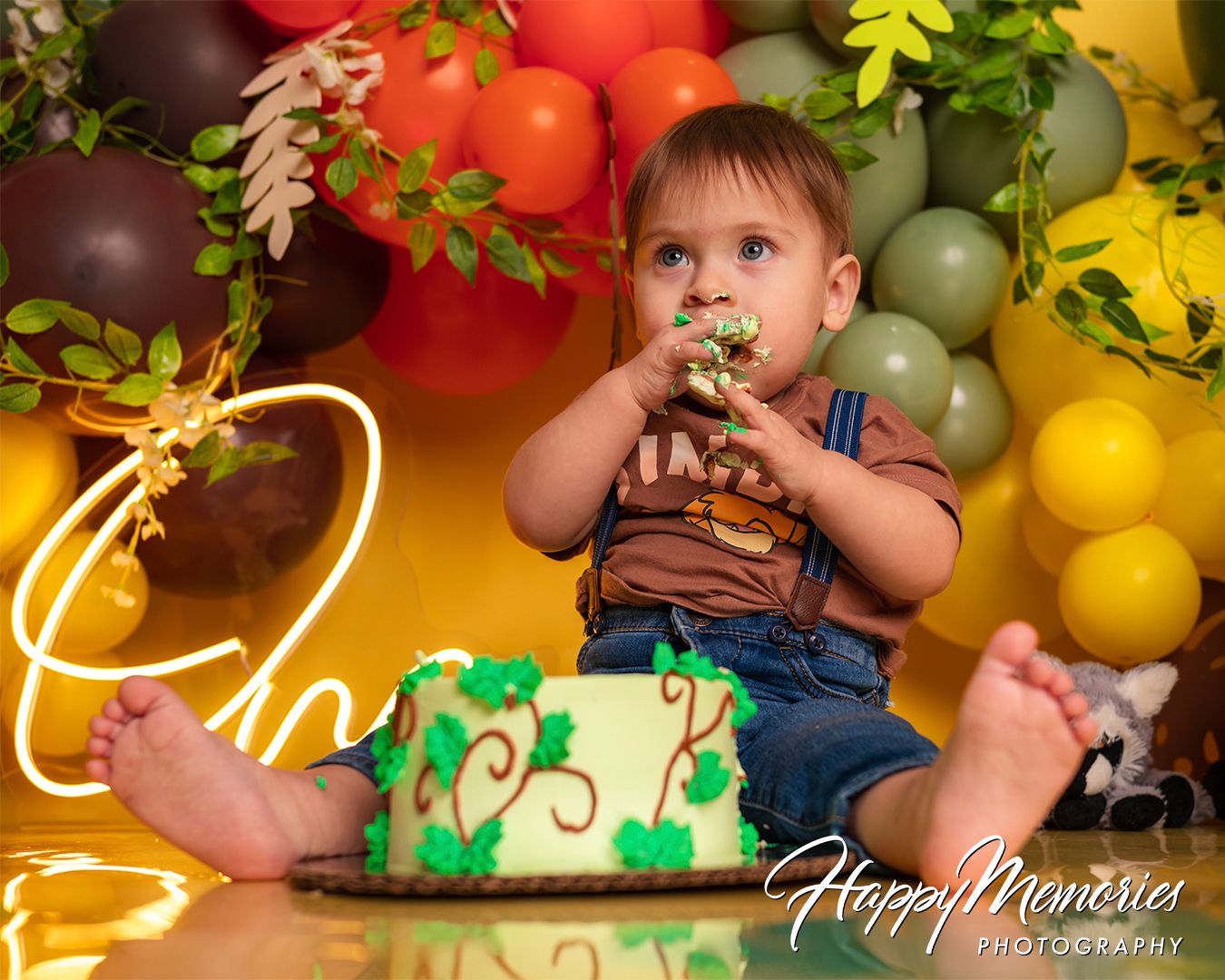 Safari-themed birthday setup with green foliage, colorful balloons, and jungle-inspired decorations.