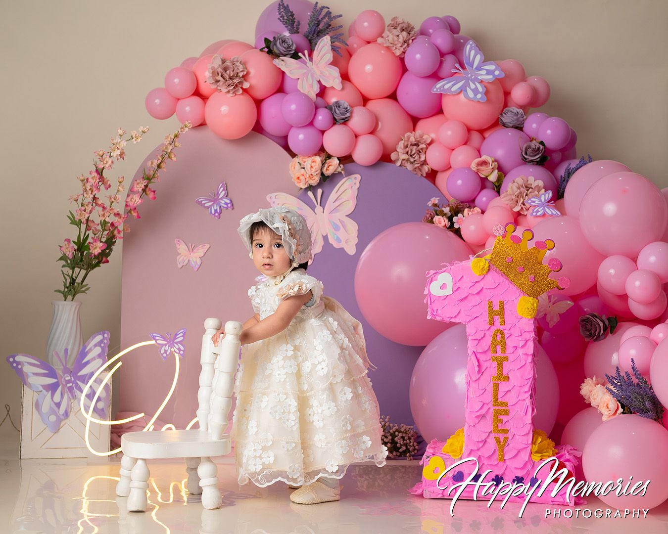 Elegant pink and purple balloon arch with butterflies decorates a dreamy party setup with floral accents.