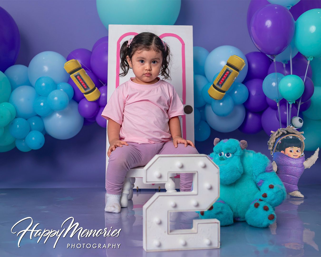 Purple and turquoise balloon display with baby bottle decorations for a first birthday celebration.