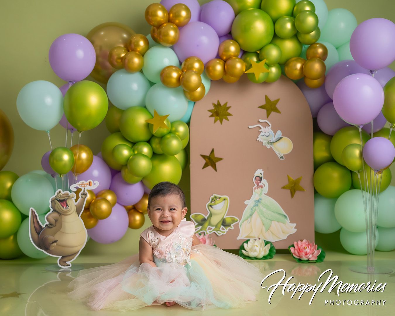 Colorful balloon garland with gold, mint, purple, and lime green balloons creates a festive backdrop for a special occasion.