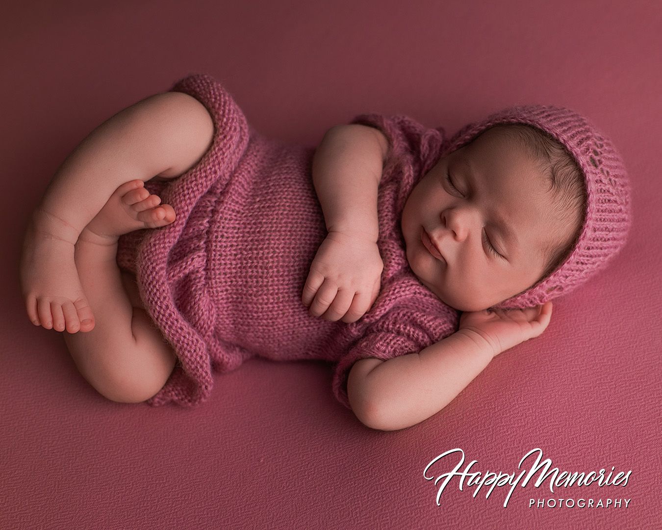Professional newborn portraits in mauve tones featuring a sleeping baby in pink knit clothing.