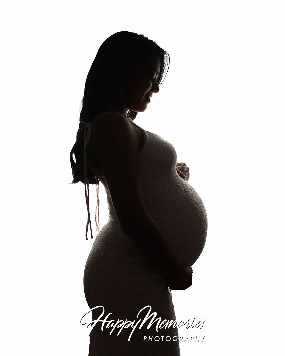 Artistic silhouette maternity portrait against dark background.