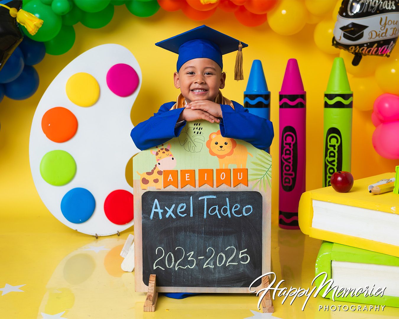 Vibrant preschool graduation scene with chalkboard sign and colorful art supply decorations.