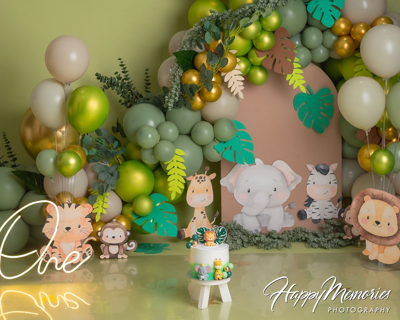 Panoramic view of a tropical-themed party setup with green and white balloons, palm leaves, and safari animal decorations.