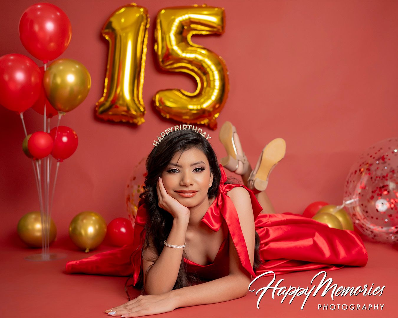 Festive quinceañera photo session with red dress and gold number balloons.